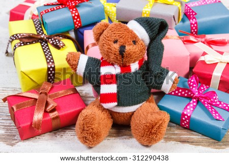 Fluffy teddy bear and heap of wrapped colorful gifts for Christmas, birthday, valentines or other celebration on old wooden white table