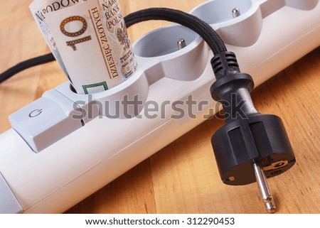 Rolls of polish currency money in electrical extension and disconnected plug, power board, concept of saving money on electricity, energy costs