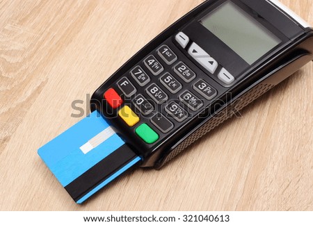 Payment terminal with credit card on wooden desk, credit card reader, paying using credit card, finance and banking concept