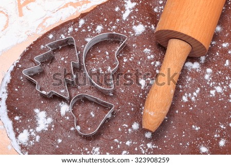 Cookie cutters in shape of heart and christmas tree, rolling pin on dough for cookies and gingerbread, accessories for baking, christmas time