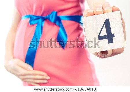 Vintage photo, Pregnant woman in pink dress with blue ribbon showing number of fourth month of pregnancy, concept of extending family and expecting for newborn 商業照片 © 