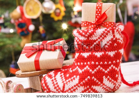 wrapped gift with ribbon for christmas on wooden sled and in red sock on background of - Wooden Sled Decoration Christmas wrapped gift with ribbon for christmas on wooden sled and in red sock on background of - Wooden Sled Decoration Christmas