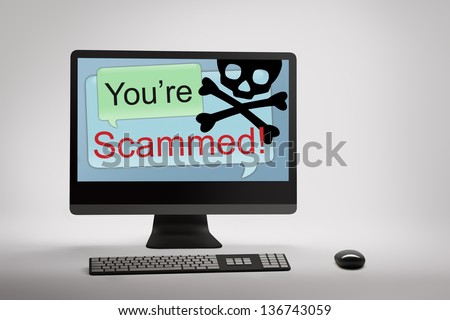 Desktop computer displaying conceptual internet fraud and scam warning on screen