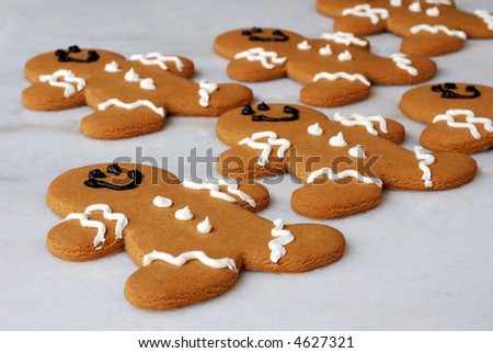 Freshly baked gingerbread men on marble pastry board.  Shallow dof