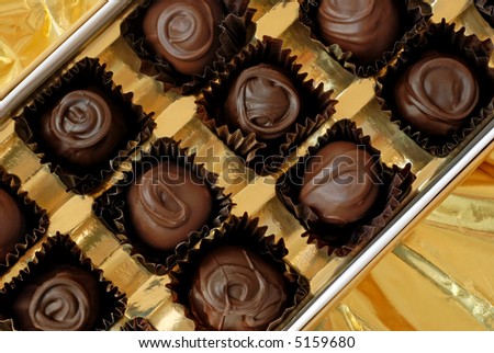 Box of chocolate cherry cordials displayed on shiny gold wrapping paper