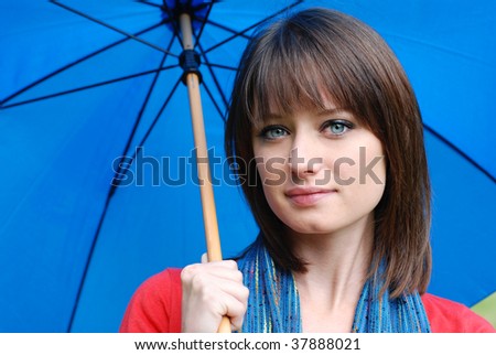 Colorful outdoor portrait of beautiful brunette with blue umbrella.  Close-up with shallow dof.