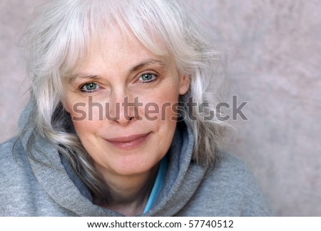 Casual portrait of happy mature woman with natural white hair and minimal makeup.