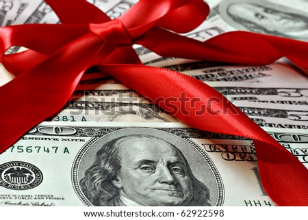Holiday gift of money.  100 and 50 dollar bills with red satin ribbon.  Macro with shallow dof.
