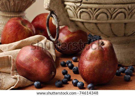 Artistic non traditional fruit bowl still life with fresh fruit scattered at base of stone bowl. Soft natural lighting for effect. Closeup with shallow dof.