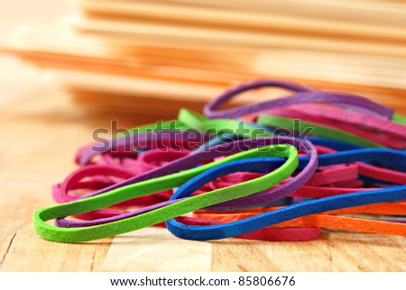 Brightly colored rubber bands with stack of manilla folders in soft focus in background.  Macro with extremely shallow dof.