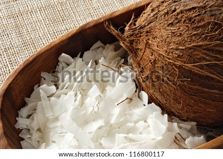 Coconut flakes with whole coconut in wooden bowl.  Macro with shallow dof.
