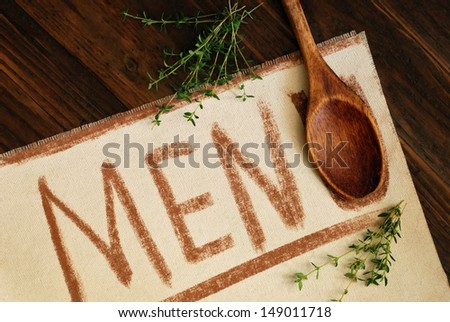 Old fashioned menu concept with casual hand printed letters (chalk on canvas),vintage wooden spoon, and fresh thyme on rustic wood background.