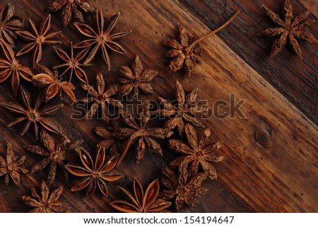 Star anise on rustic, dark wood background.  Low key still life with directional natural lighting for effect.