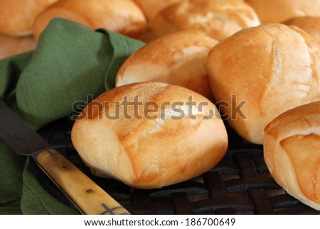 Still life of freshly baked dinner rolls on cast iron trivet with antique butter knife. Closeup with shallow dof.