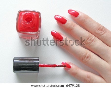 woman\'s nails with manicure and vial of red color nail polish