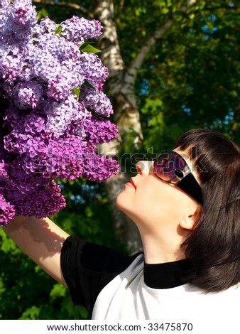 woman in sun glasses smell bouquet of lilac flowers