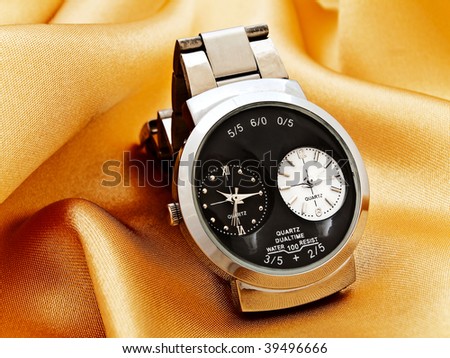 fashioned man watch at the golden fabric
