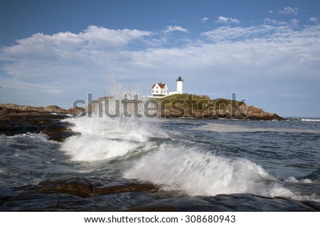 Nubble Light is an island beacon located close to the shore in Maine, surrounded by surf breaking at high tide.