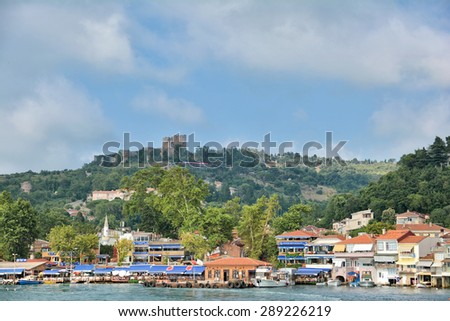 ISTANBUL, TURKEY, JUNE 8, 2013 : Coastline of Anadolu Kavagi, a famous fishing town at the edge of  Bosphorus with many restaurants and touristic facilities. Yoros Castle can be seen at hilltop