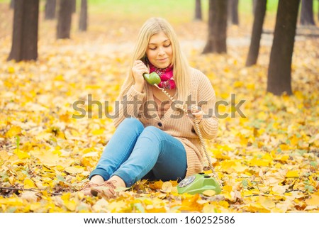 young woman talking on vintage phone in autumn park