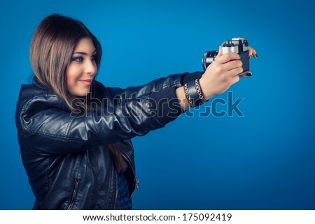 beautiful young woman holding camera on blue background