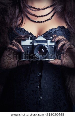 woman wearing corset and fur and holding vintage camera