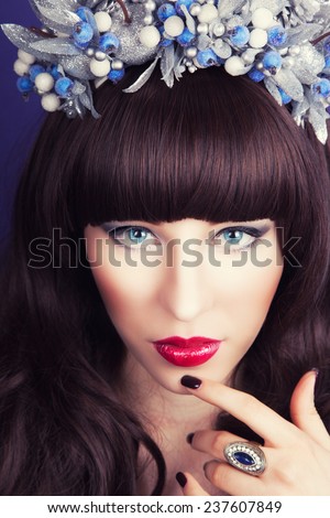 beautiful young woman wearing designer wreath and posing against blue background