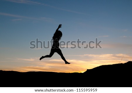 Young woman jumps for joy punching the air at sunset. Figure in silhouette