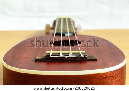 An ukulele on wood background , small guitar