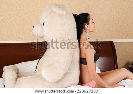 beautiful woman sitting back to back with a big teddy bear