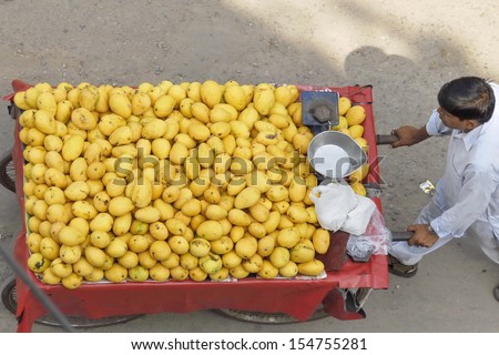 NEW DELHI, INDIA - MAY 23: Unidentified street vendor pushes his cart full of mangoes on a Main Bazaar street on May 23, 2009 in New Delhi, India. May is mangoes picking season in India.