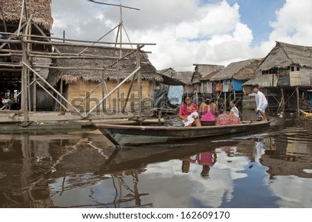 IQUITOS, PERU - APRIL 29: Unidentified Peruvian family in traditional boat float on water street in Belen, Iquitos, Peru on April 29, 2010. Boats are only mode of transport in a poor area of Iquitos.
