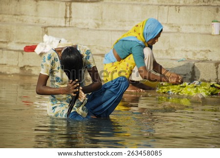 VARANASI, INDIA - APRIL 30: Unidentified Indian woman washes her hair in The Ganges river on April 30, 2009 in Varanasi, India. For most Indian women washing hair in the river is daily activity.