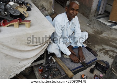 DELHI, INDIA - MAY 23: Unidentified street shoemaker sharpens his tool a Main Bazaar street on May 23, 2009 in Delhi, India. Shoeshine is the most common type of small business in India.