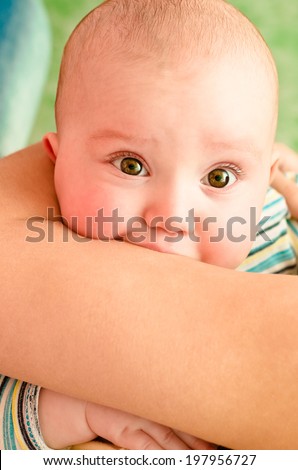 Portrait of a cute baby biting hand of mother
