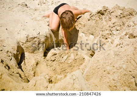 Child plays in the sand on the beach