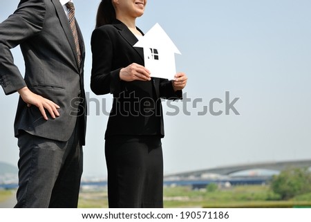 Businessmen suit standing back the blue sky with a house made ??of white paper