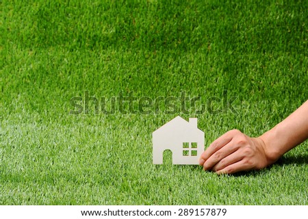 Green grass, house and human hand