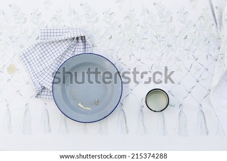 conceptual photo of empty tin plate and cup on table with tablecloth, copy space