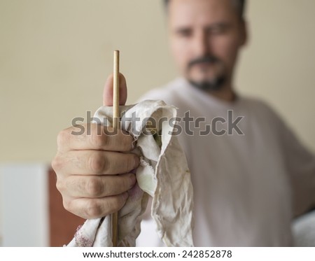 Close up of painters hand measuring proportions with the handle of the brush, thumb method