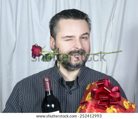 Male winking holding rose in mouth, bottle of wine and present