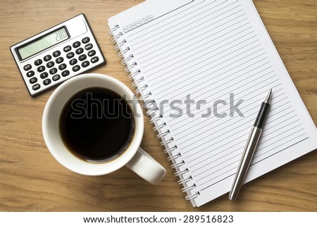 Book, pen, a cup of coffee and small calculator on wooden background