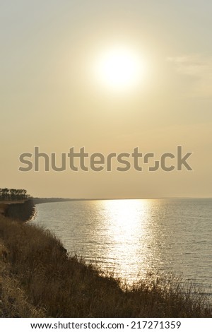 sunset above the sea and field