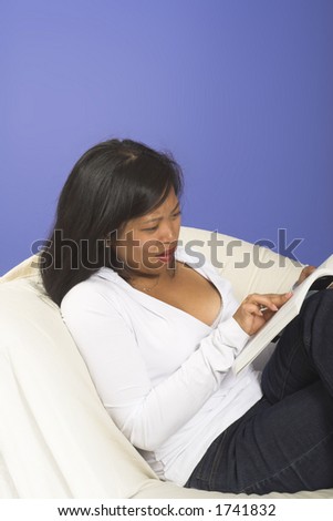 girl trying to read a book on couch over blue background