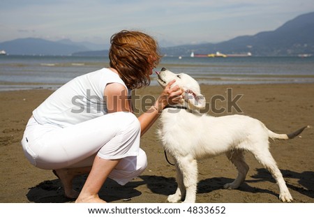 woman giving a kiss to her dog on the beach