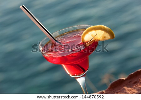 Cosmopolitan Cocktail with slice of lemon, against sea