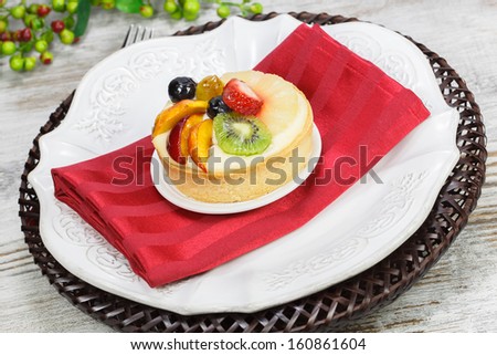 Fruit tart pies on white plate with forks , close up. A delicious fruit tart made with strawberries, peaches, grapes,  mango and kiwi.