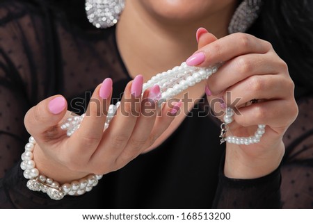 Beads pearls. Beautiful woman hands  with pink manicure holding white pearl necklace.. Pearls and Nails concept