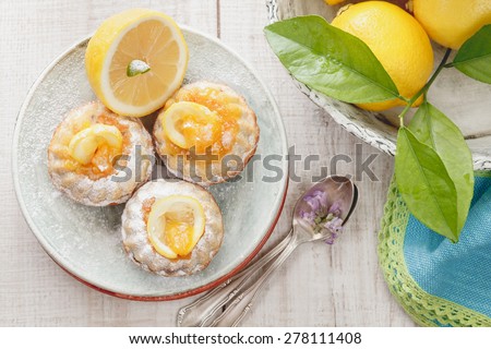 Mini lemon bundt cakes.  Mini lemon bundt cakes dusted with icing sugar and fresh lemons over rustic wooden background. Macro, selective focus. Natural light