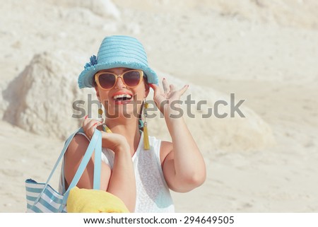 Woman with towel bag on the sandy beach. Beautiful woman smiling and  carrying bag on the sandy beach. Summer vacation concept. Vintage style, selective focus